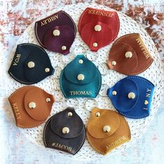 six different color leather coin purses sitting on a white plate with the name thomas written on them