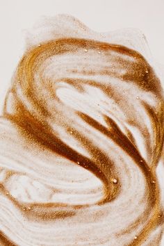 a close up view of some liquid on a white surface with brown and yellow streaks