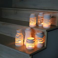 some jars with lights on them are sitting on the stairs and one is lit up