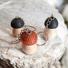 two wooden and black acrylic beads are on a rock with silver chains hanging from them