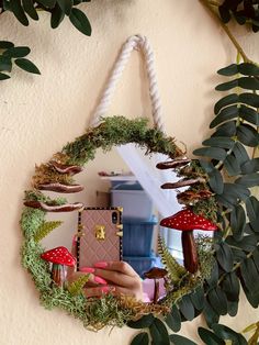 a mirror hanging on the side of a wall with plants and mushrooms in front of it