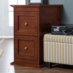 a nightstand with two drawers and a suitcase on it next to a bed in a room