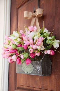 a bunch of pink and white flowers in a vase on a doorknob with a bow