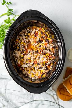 a crock pot filled with chicken, beans and rice next to sliced carrots