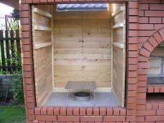 an outdoor wood fired pizza oven built into the side of a brick building with a bench in it