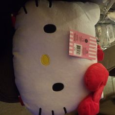 a hello kitty stuffed animal laying on top of a pillow with a tag attached to it