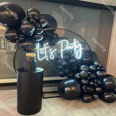 black balloons are on display in front of a sign that says let's party