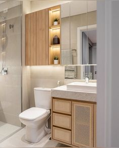 a bathroom with a toilet, sink and shower stall in the corner is lit by recessed lighting