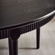 a close up of a black table on a wooden floor with no one around it