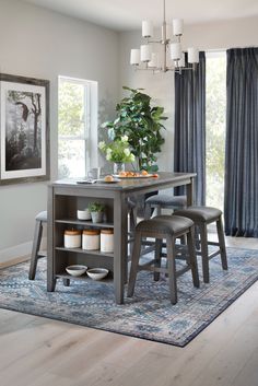 a dining room table with two chairs and a potted plant in the center on a rug