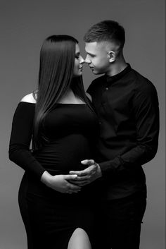 a pregnant couple kissing while standing next to each other