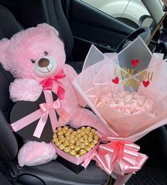 a pink teddy bear sitting in the back seat of a car next to a bouquet of flowers