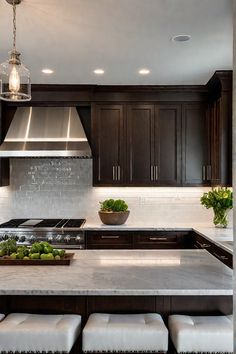 a kitchen with marble counter tops and dark wood cabinets, along with white stools