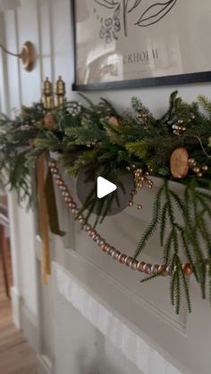 a fireplace mantel decorated with greenery and gold ornaments on it's mantle