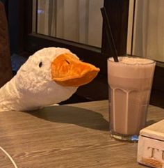 a stuffed duck sitting next to a glass of milk