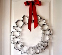 a metal wreath with red ribbon hanging on the front door, decorated with cookie cutters