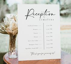 a reception sign sitting on top of a table next to a vase filled with flowers