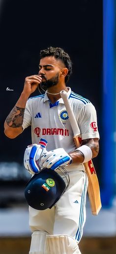 a man in white uniform holding a cricket bat and helmet