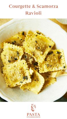 a white bowl filled with ravioli on top of a wooden table