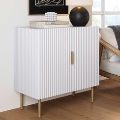 a white cabinet sitting next to a window in a room with wooden floors and walls