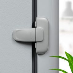 a door handle on the side of a white door with a green plant next to it