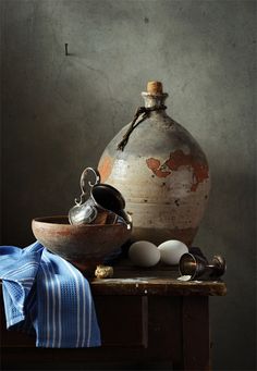 an old vase sitting on top of a wooden table next to other items in front of it