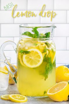 a pitcher filled with lemonade next to sliced lemons