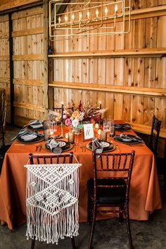 the table is set with two chairs and an orange table cloth