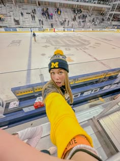 a woman is taking a selfie in the stands at a hockey game while wearing a beanie