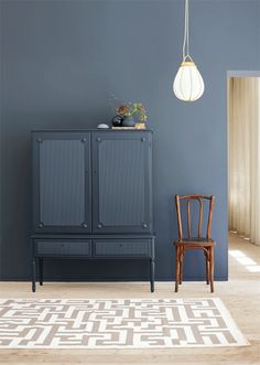 a chair and cabinet in a room with a rug on the floor next to it