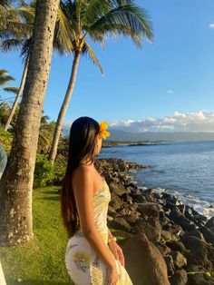 a woman holding a frisbee standing on top of a lush green field next to the ocean