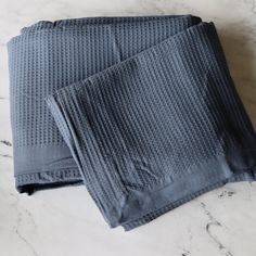 two folded gray towels sitting on top of a marble counter