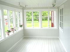 an empty room with white walls and wood flooring, two windows are open to the yard