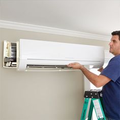 a man working on an air conditioner in a room that has been painted white