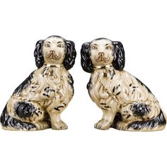 two black and white dog figurines sitting next to each other on a white background