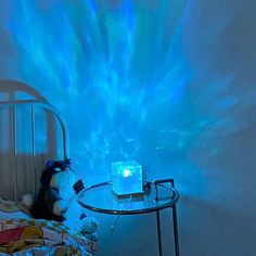 a teddy bear sitting on a bed in front of a blue light that is shining