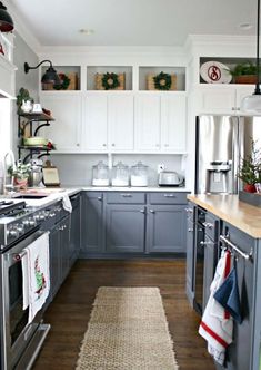 a kitchen with gray cabinets and white walls, wood flooring and an area rug in front of the stove