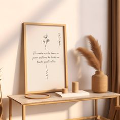 a wooden table topped with a vase filled with flowers and a framed quote on it