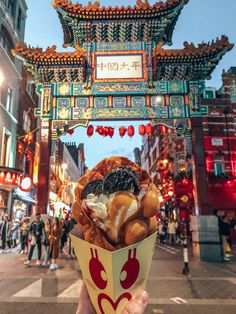 a person holding up a doughnut in front of a chinese arch