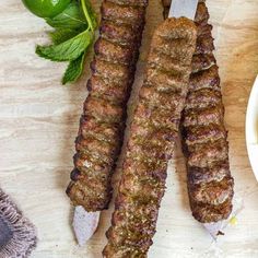 two skewers of meat sitting on top of a table next to a bowl of sauce