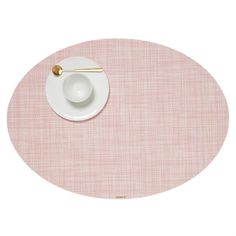 a pink place mat with a white plate and gold spoon