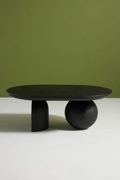 a black table sitting on top of a white floor next to a green wall in an empty room