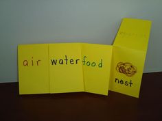 two pieces of yellow paper with words written on them sitting next to each other in front of a white wall