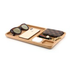 a wooden tray with sunglasses, wallet and other items in it on a white background