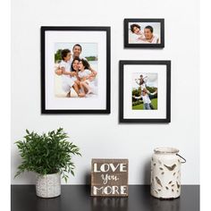 three framed photos hang on the wall above a table with a plant and other items