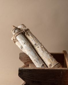 two pieces of wood tied together in a wooden box on top of a table next to a wall