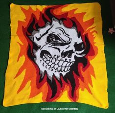 a knitted blanket with an image of a skull in flames on the front and back