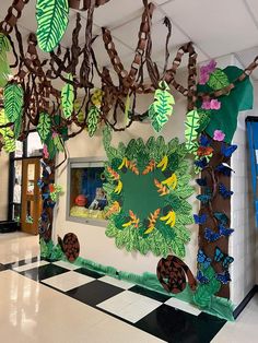 a classroom decorated with paper cut outs and leaves on the wall, along with other decorations