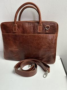 The 16 inch genuine leather laptop bag for men could have a stylish and sturdy design with durable stitching and quality metal accessories. It can have multiple compartments and pockets for organization, including a dedicated laptop compartment with a soft lining for protection. The straps could be adjustable for wearing comfort, and the genuine leather material would give it a refined look and durability. The design of the bag could be minimalist, with clean lines and subtle details, fitting an Classic Leather Laptop Bag With Sleeve, Leather Laptop Bag With Sleeve In Satchel Shape, Leather Laptop Bag With Luggage Sleeve For Office, Office Leather Laptop Bag With Luggage Sleeve, Leather Briefcase With Laptop Sleeve For Office, Modern Leather Laptop Bag With Sleeve, Brown Rectangular Laptop Bag With Sleeve, Brown Laptop Bag With Sleeve For Daily Use, Formal Leather Laptop Bag With Sleeve