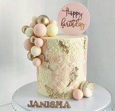 a birthday cake decorated with pink, gold and white decorations on top of a table